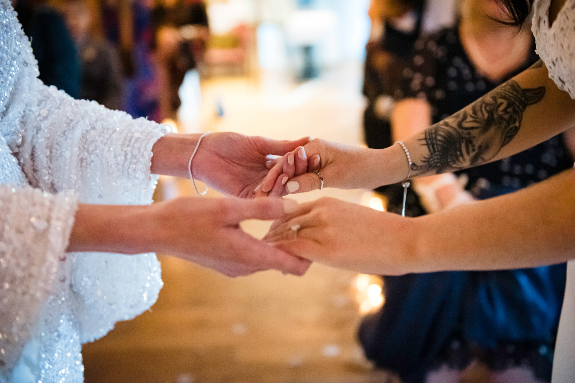 Close-up of brides holding hands during their wedding ceremony .