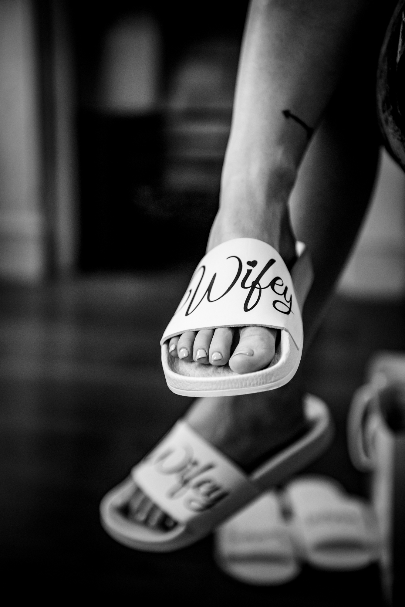 White bridal sliders with “Wifey” text in black lettering, captured in soft window light.