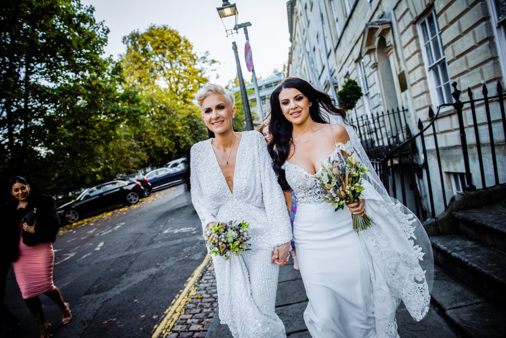 Two brides walking hand in hand through Clifton’s Georgian streets after their ceremony.