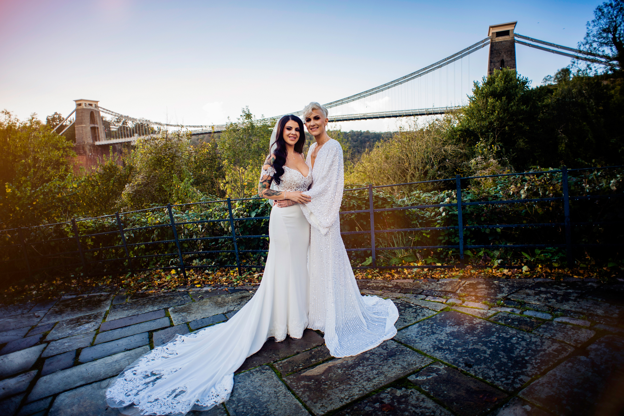 Romantic wedding portrait of two brides in front of Clifton Suspension Bridge at sunset.