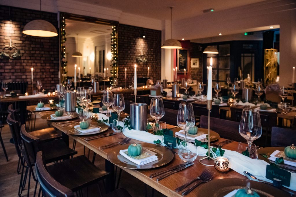 Elegant dinner setup with gold chargers, candles, and mini green pumpkins for a Halloween-themed wedding.