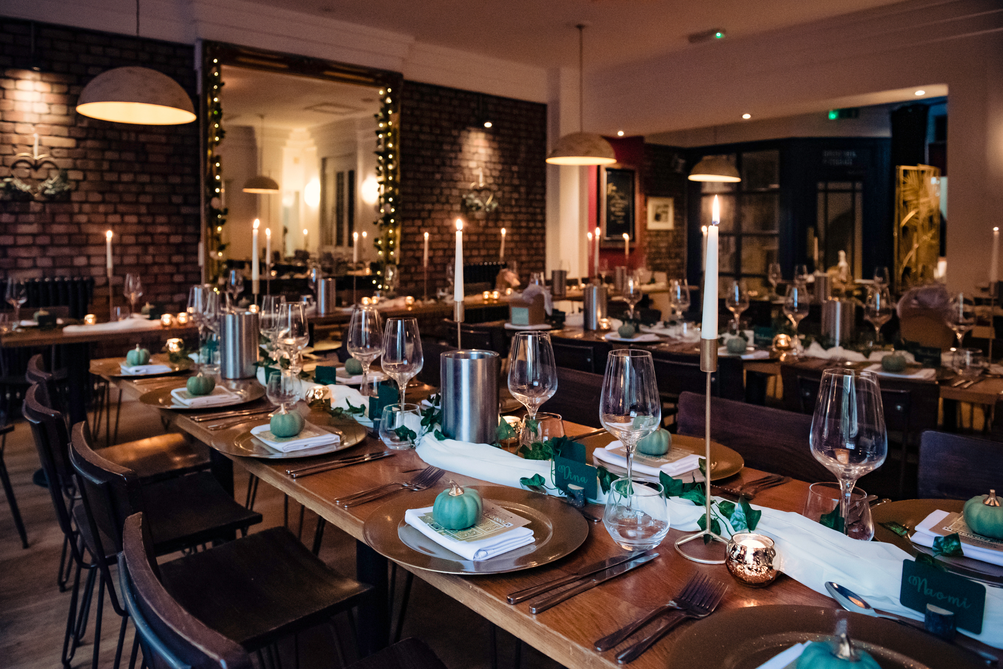 Elegant dinner setup with gold chargers, candles, and mini green pumpkins for a Halloween-themed wedding.