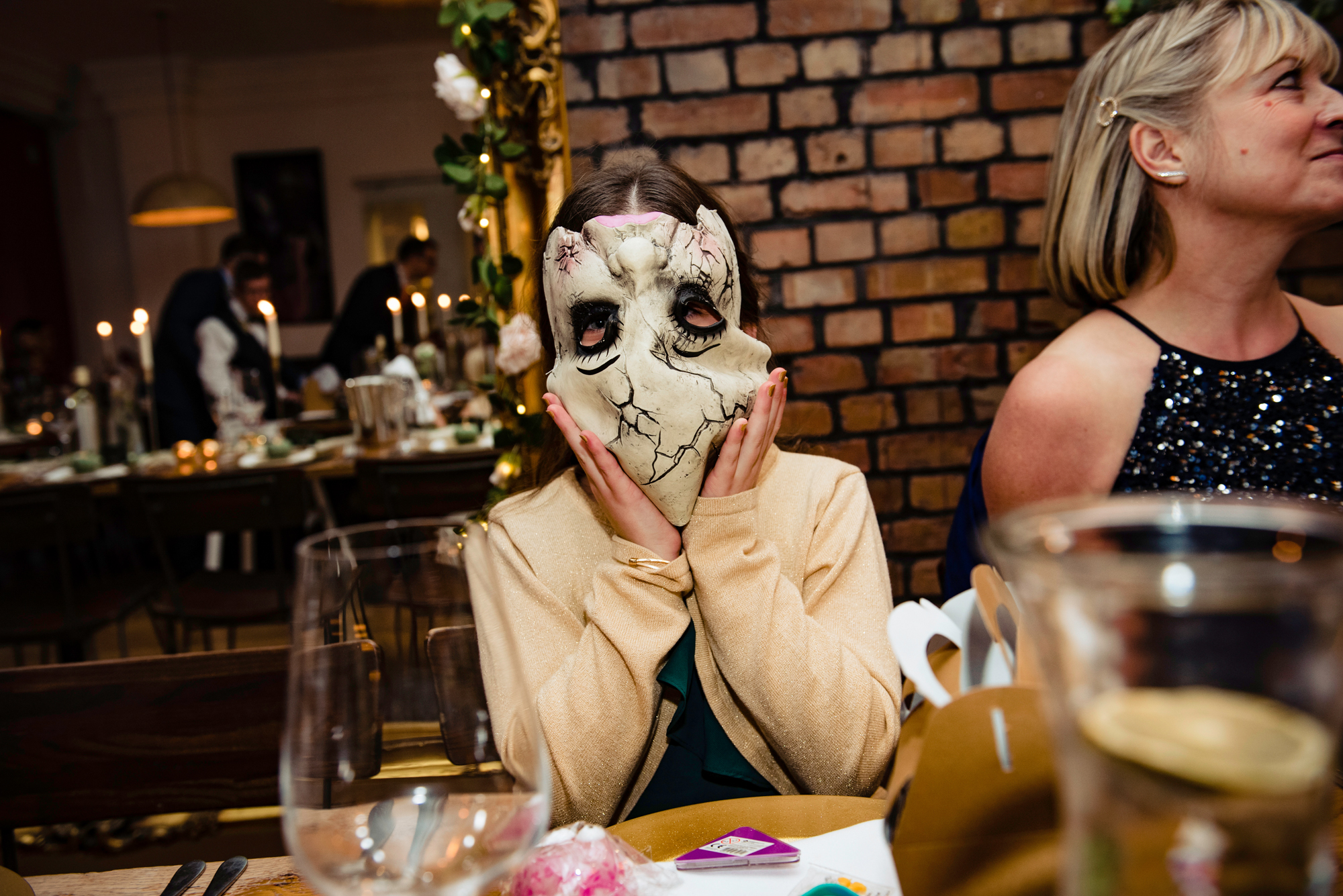 Wedding guest kid is wearing a Halloween mask during the wedding reception