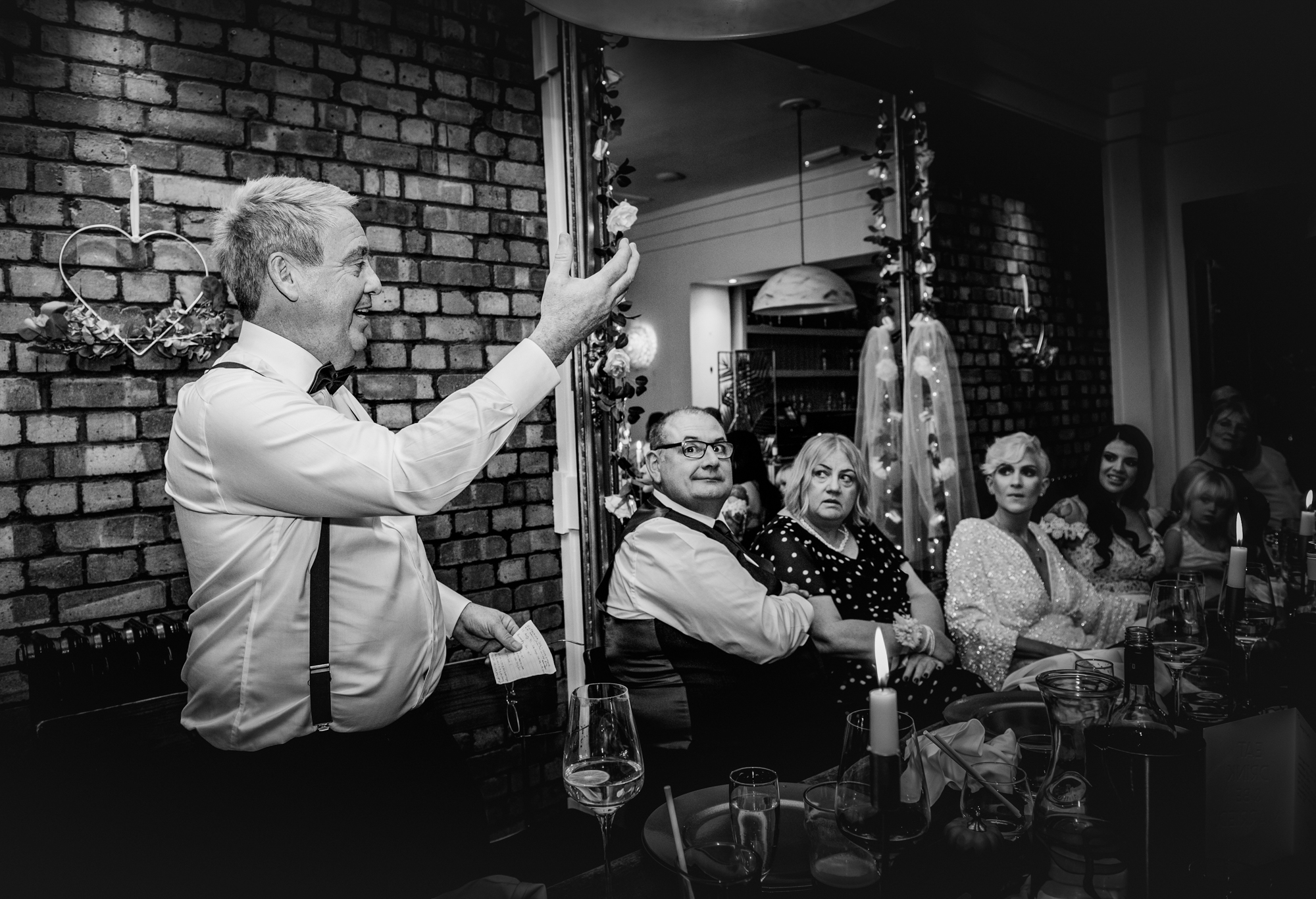 Father of the bride giving a heartfelt toast while guests listen and smile during the wedding reception.