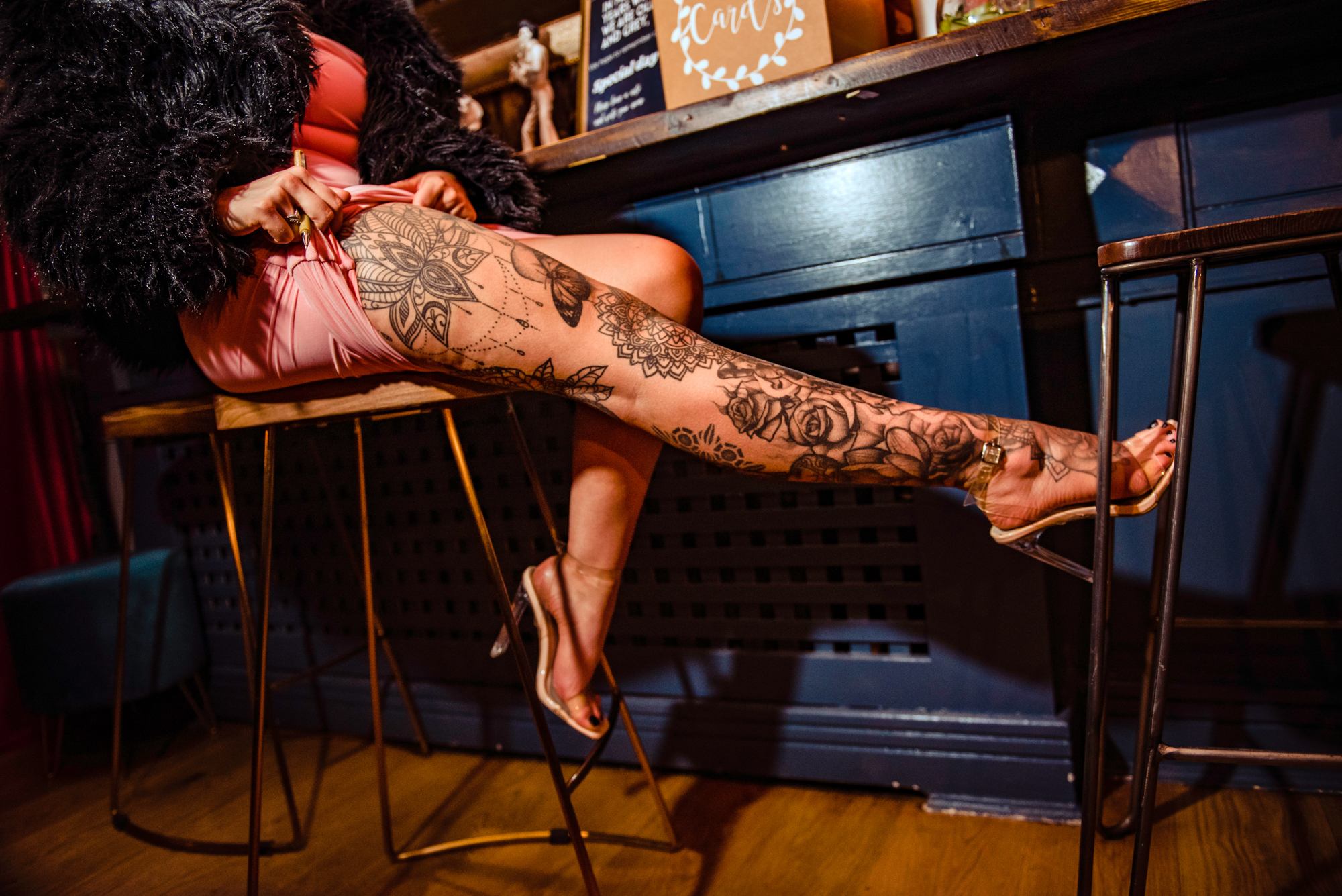 Guest showing a detailed leg tattoo in heels and a pink dress.