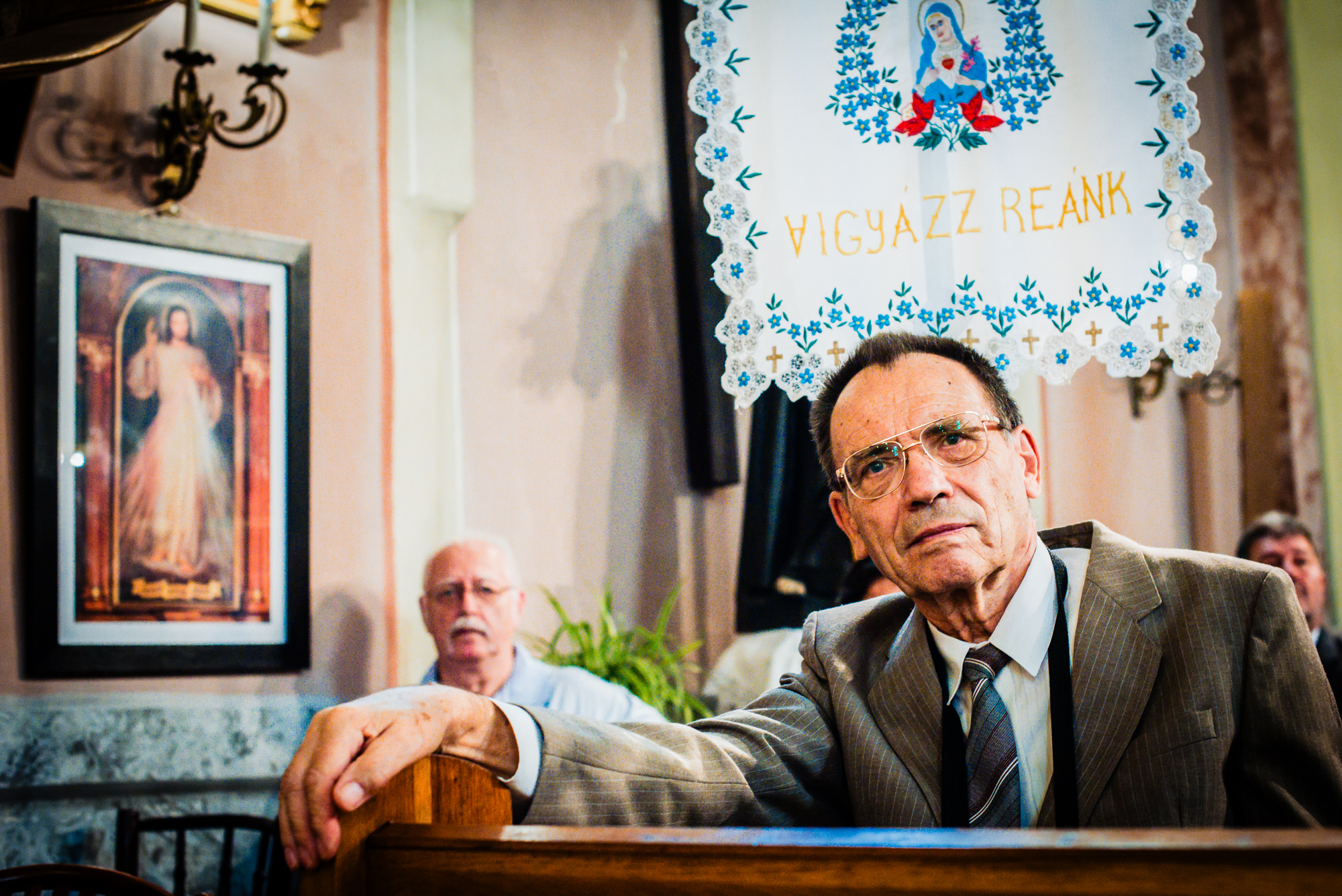 Elderly wedding guest watching the ceremony inside a decorated Hungarian church.