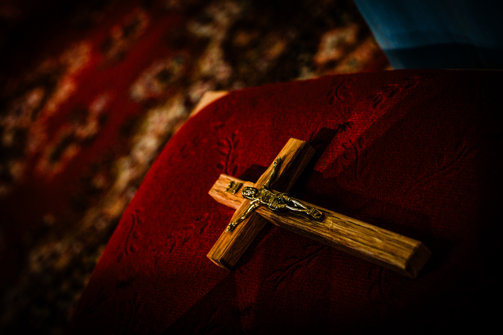 Wooden crucifix resting on a red velvet chair during a Hungarian church wedding ceremony.