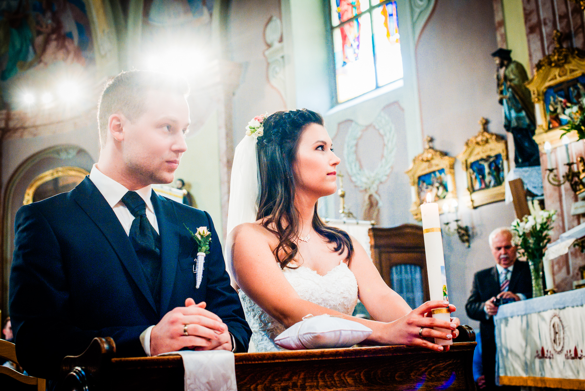 Bride and groom holding a unity candle during a traditional church wedding ceremony in Hungary.