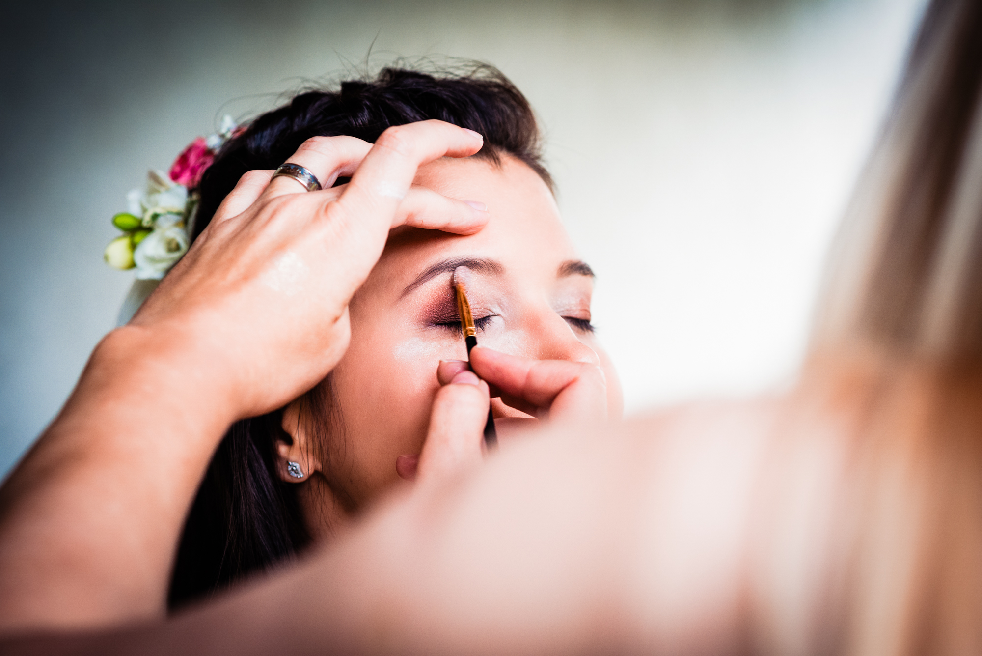 Makeup artist applying shimmering eyeshadow to the bride during morning wedding preparations in Hungary.