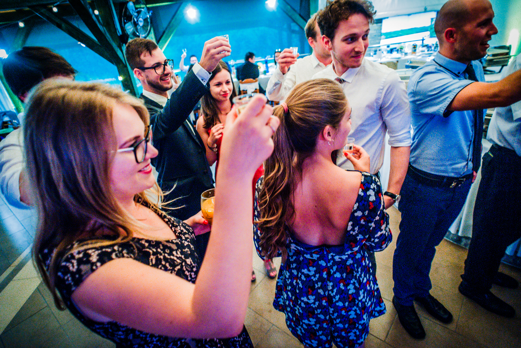 Wedding guests raising pálinka shots together during lively Hungarian wedding reception celebration.