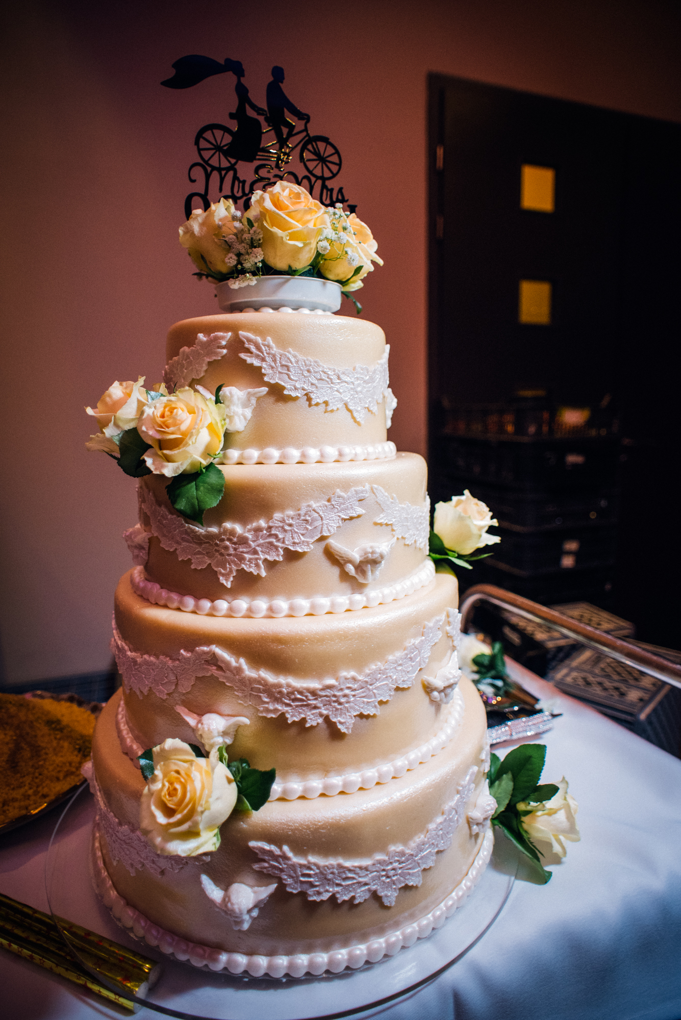 Elegant multi-tier wedding cake with lace details and floral decoration at Budapest wedding venue.