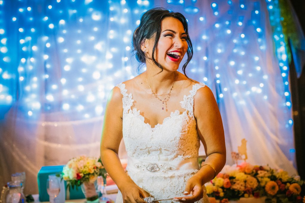 Bride laughing in front of fairy lights during joyful Budapest wedding reception.