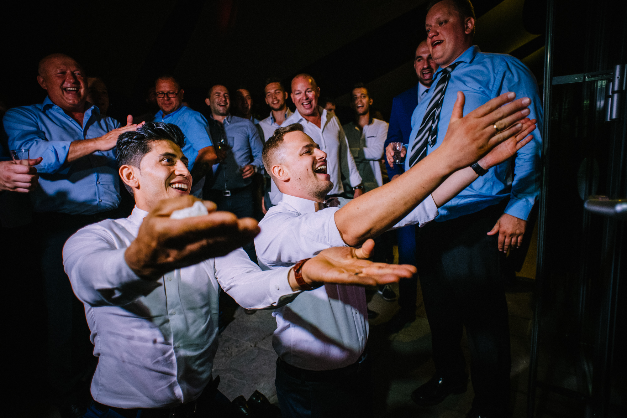 Group of men clapping and singing together during high-energy wedding celebration.