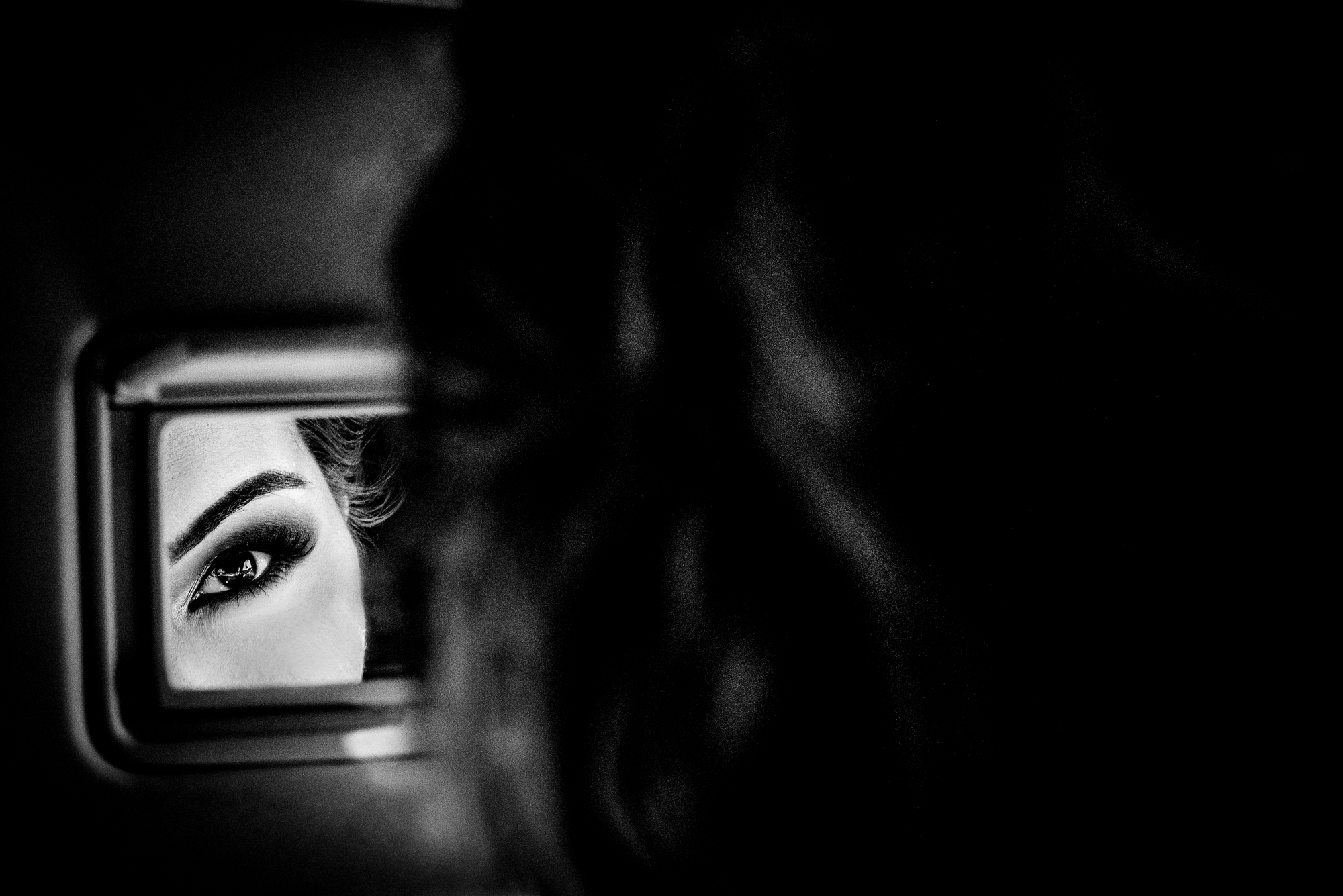 Close-up reflection of bride’s eye in mirror, intimate preparation moment.