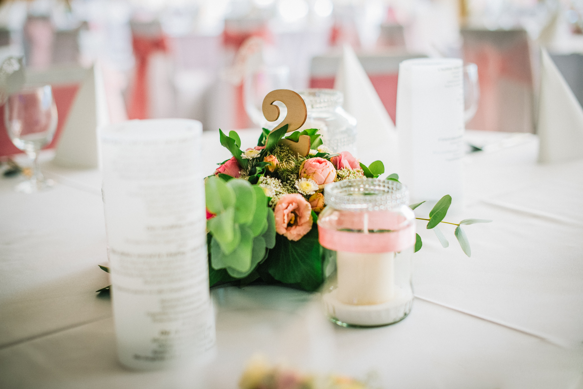 Wedding table centrepiece with flowers and candles, soft pastel reception styling.
