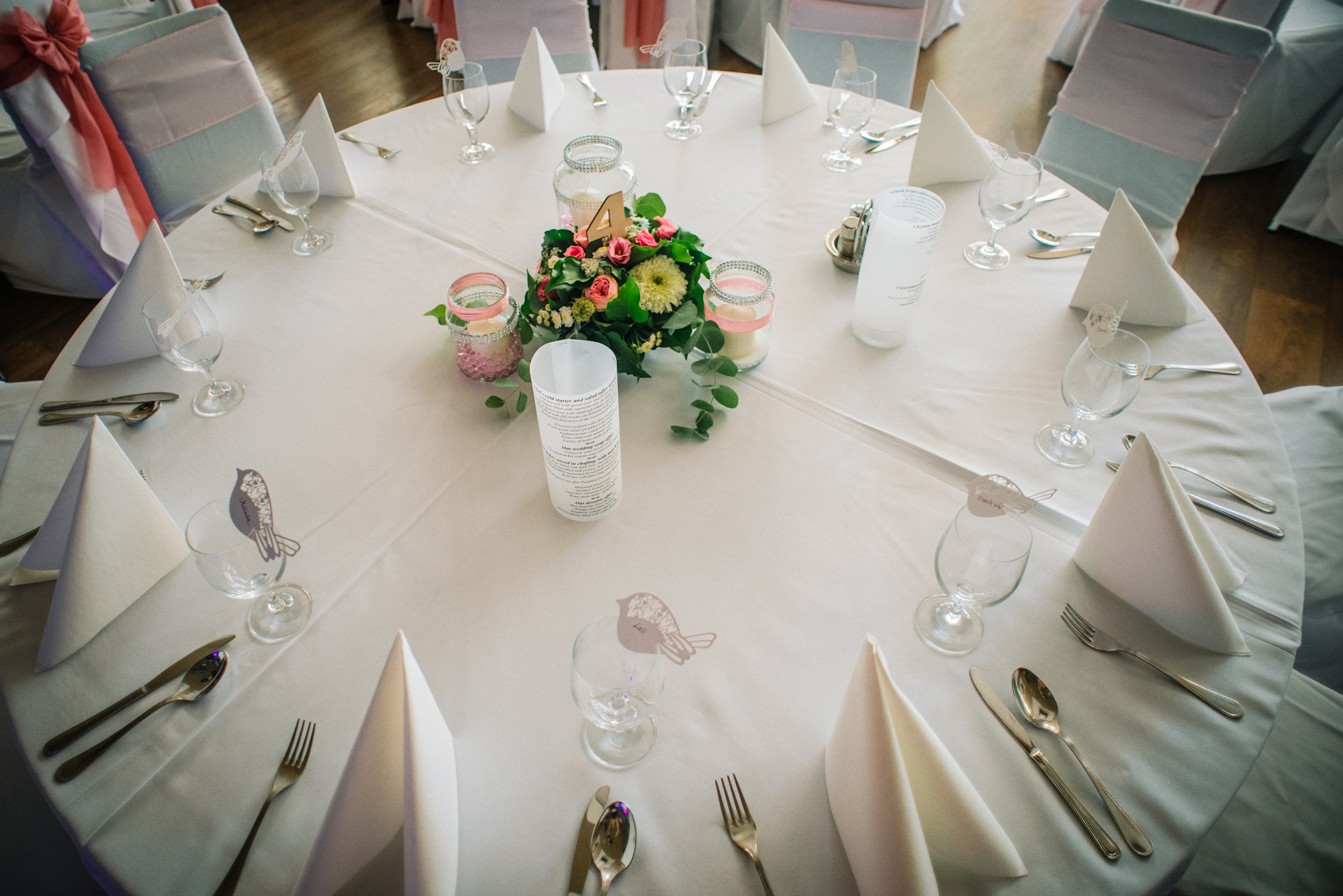 Round reception table setup with glassware and folded napkins, clean elegant styling.