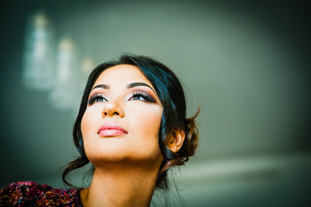 Close-up portrait of bride looking upward, natural light highlighting makeup and calm expression