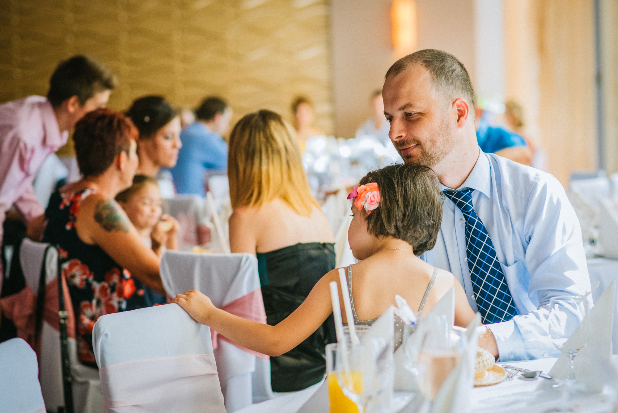 Father and daughter sitting together at reception table, warm family interaction.