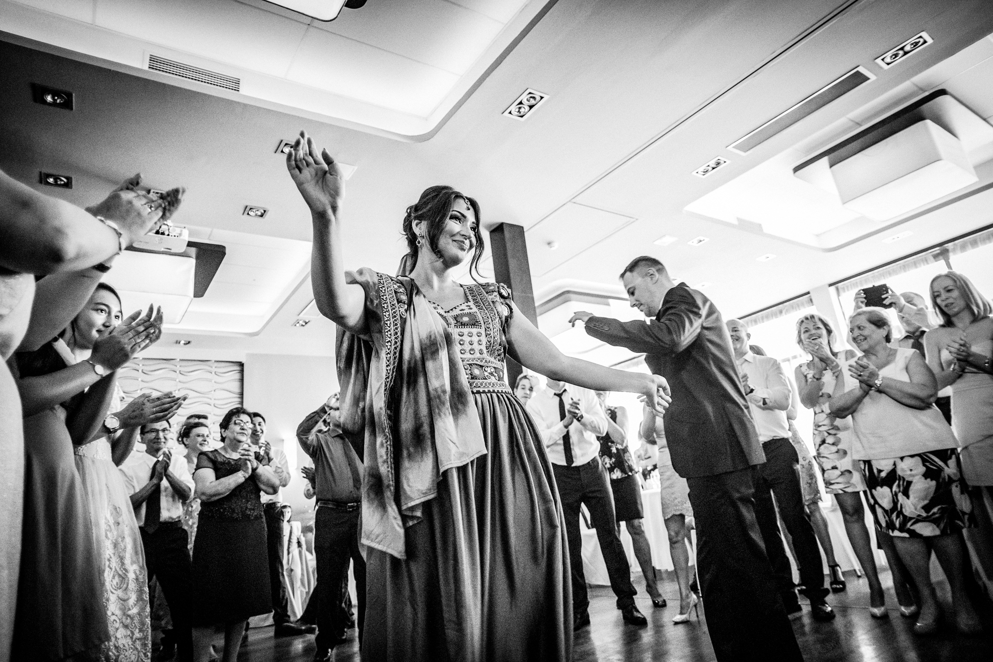 Bride dancing in traditional afghan wedding dress surrounded by guests.