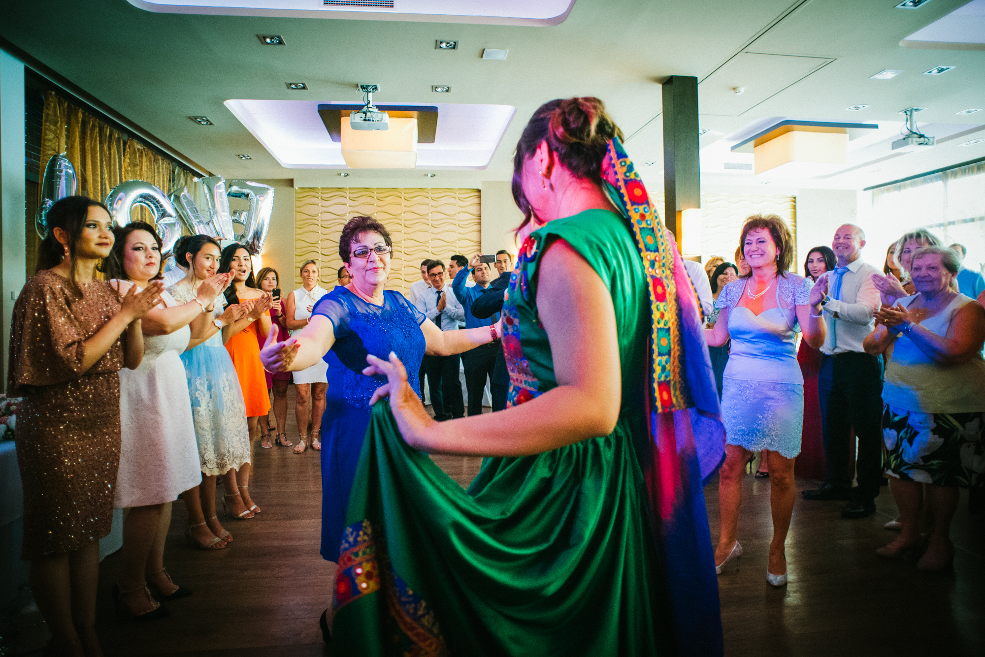 Guests forming circle around dancing couple in traditional attire, cultural wedding moment.