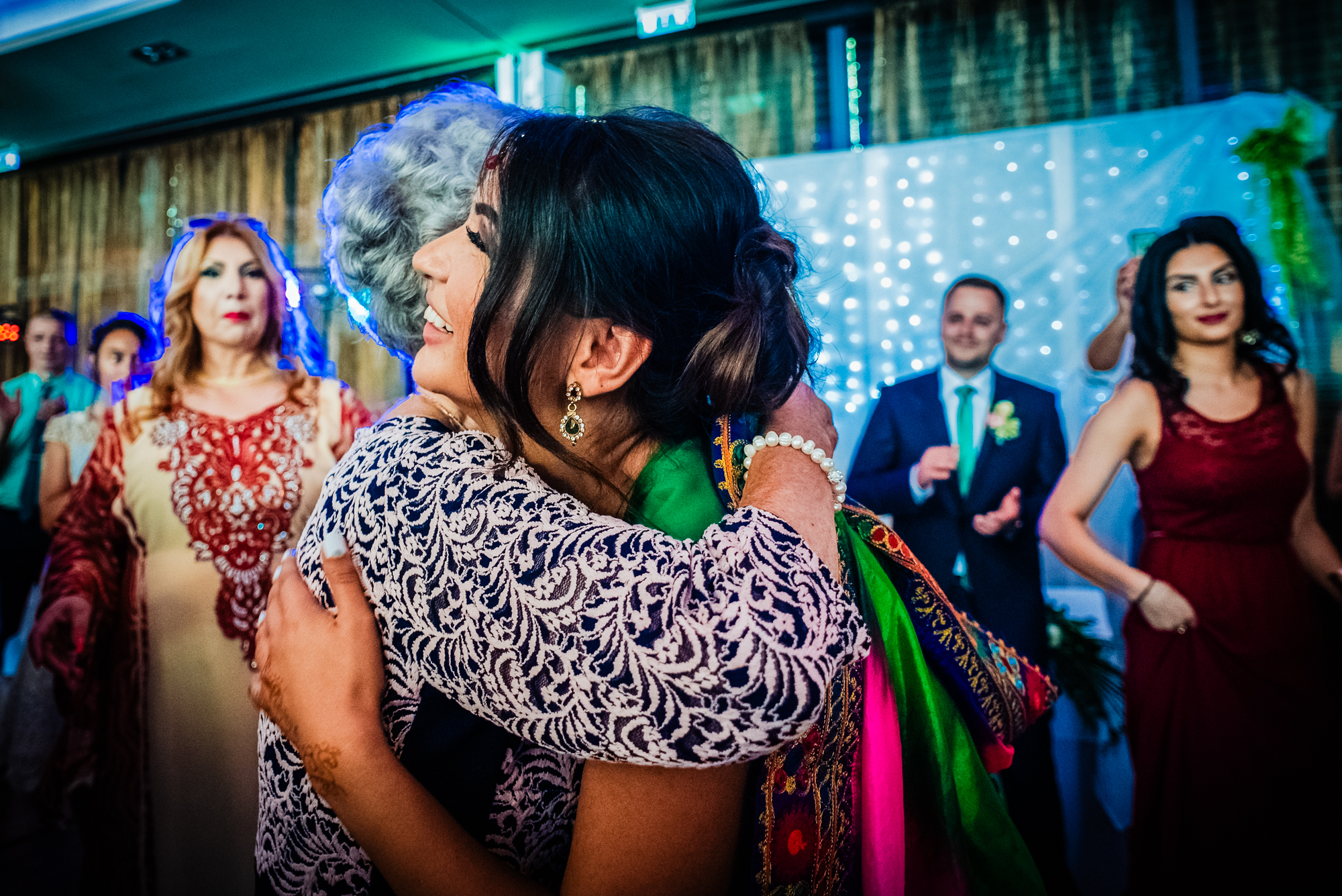 Bride hugging older guest during reception, emotional candid moment.