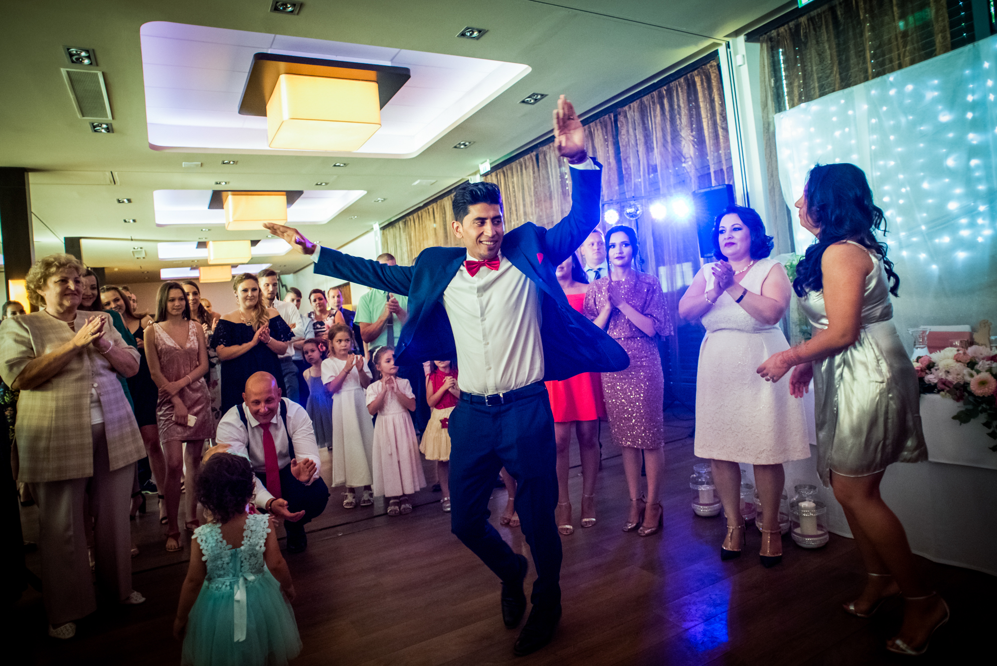 Wedding guest dancing in centre of crowd with guests watching, energetic reception scene.