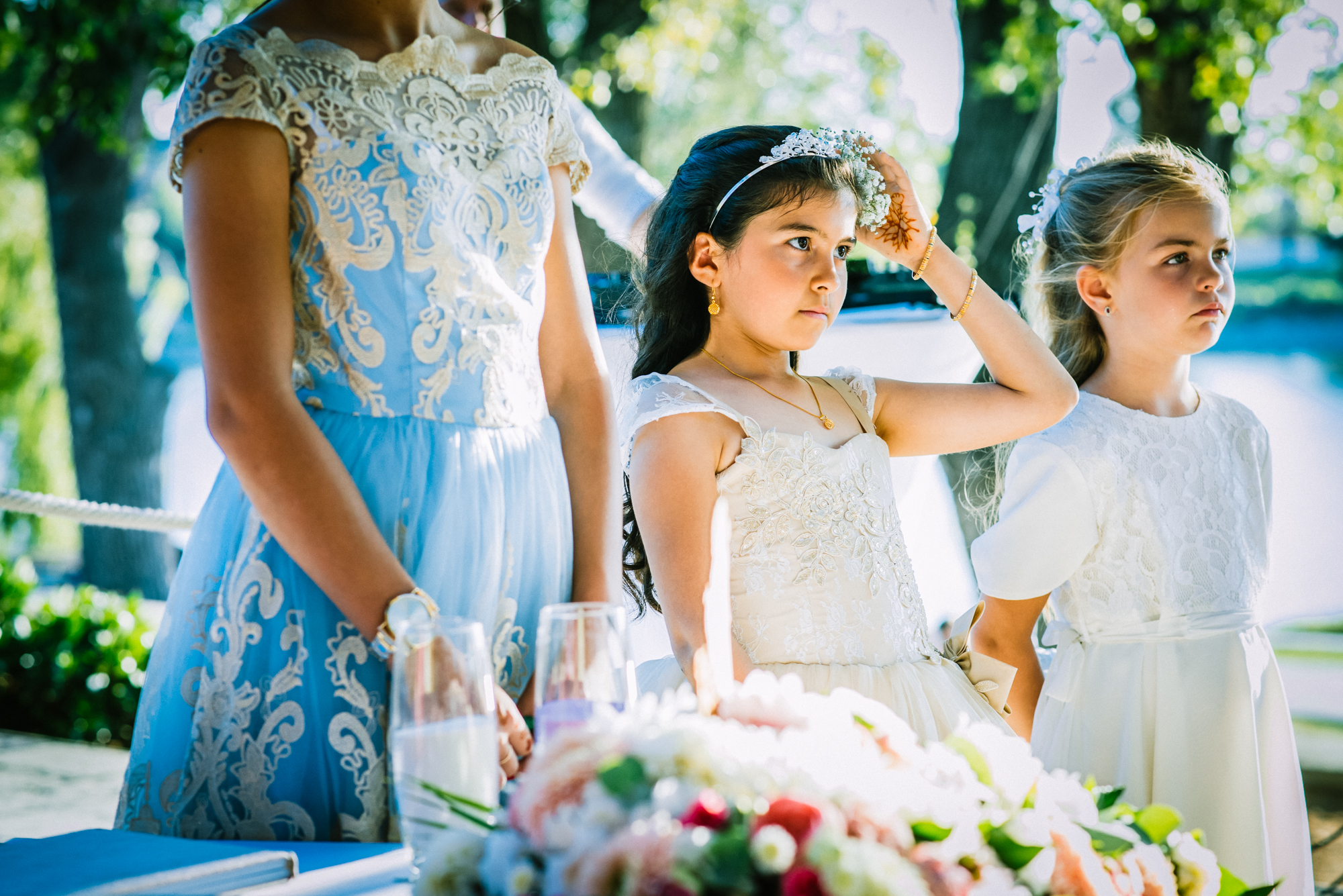 Bridesmaids and flower girls standing beside wedding cake table during ceremony at Öbölház Budapest.