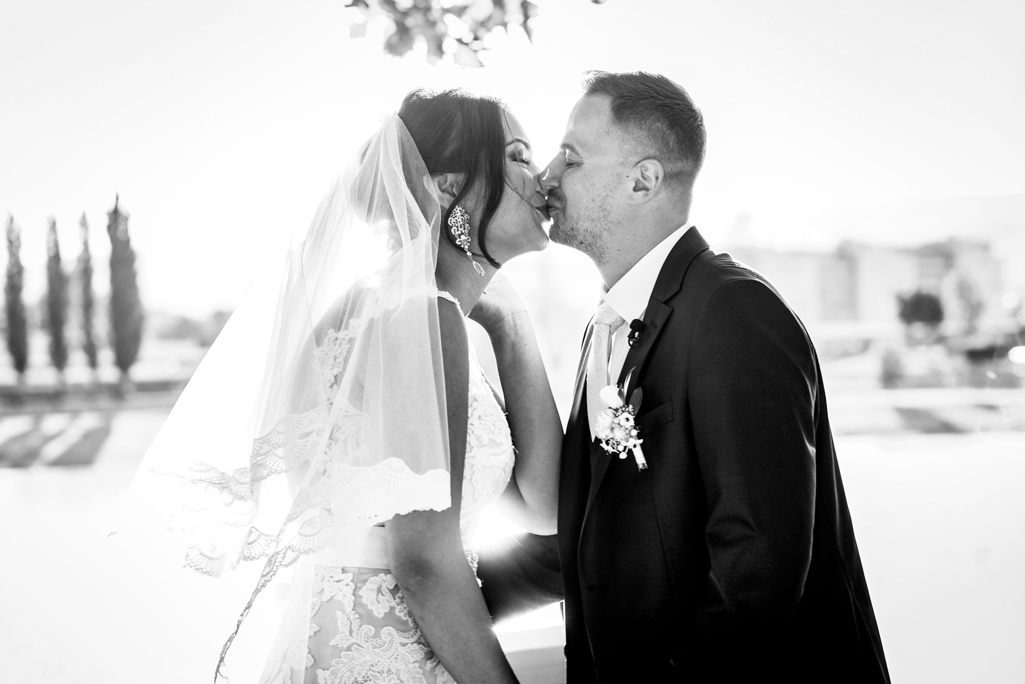 Bride and groom sharing a kiss in soft backlight during romantic Budapest wedding moment.