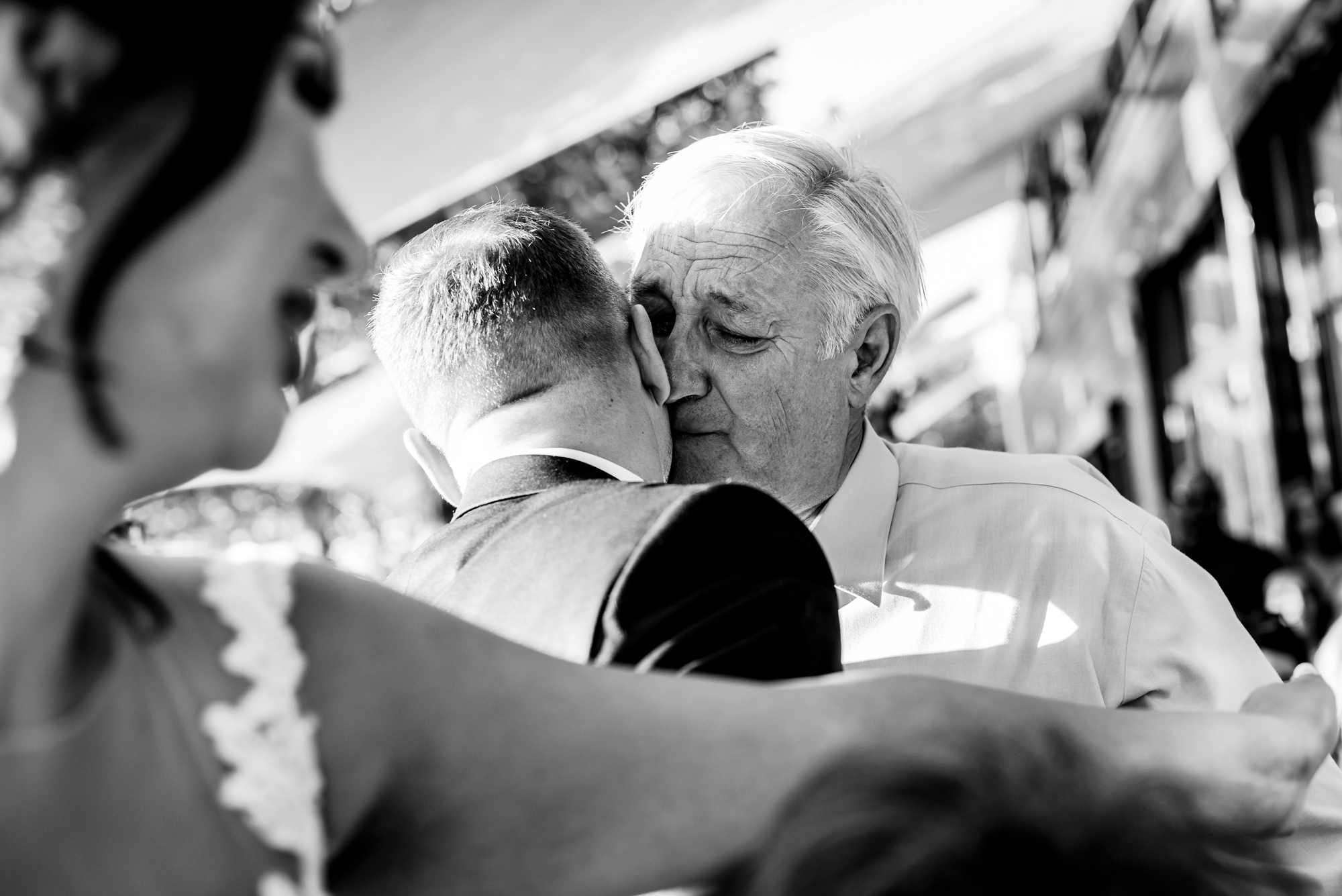 Emotional embrace between groom and older family member during wedding reception in Budapest.