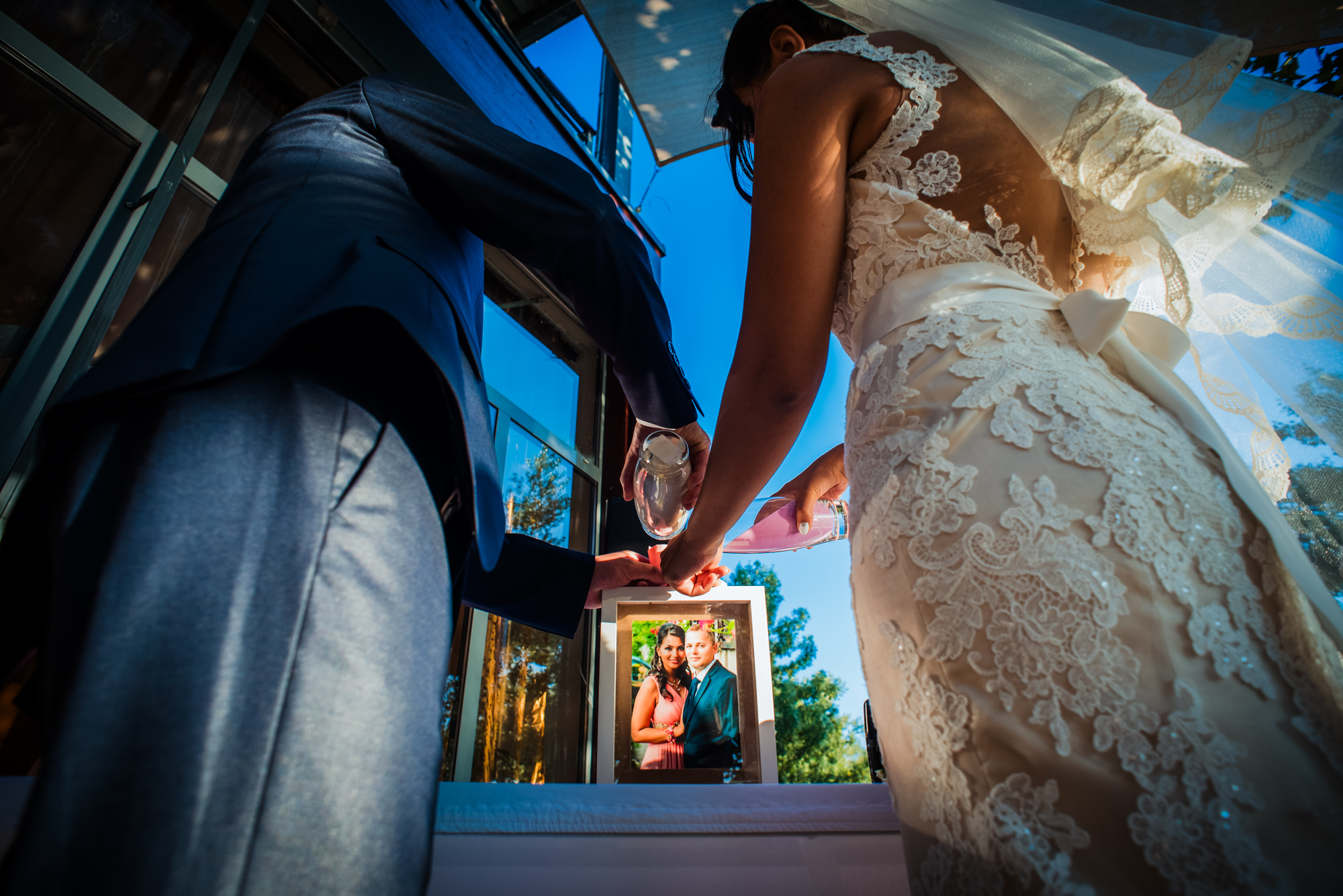 Bride and groom pouring sand ceremony into frame with photo at Öbölház Budapest wedding.