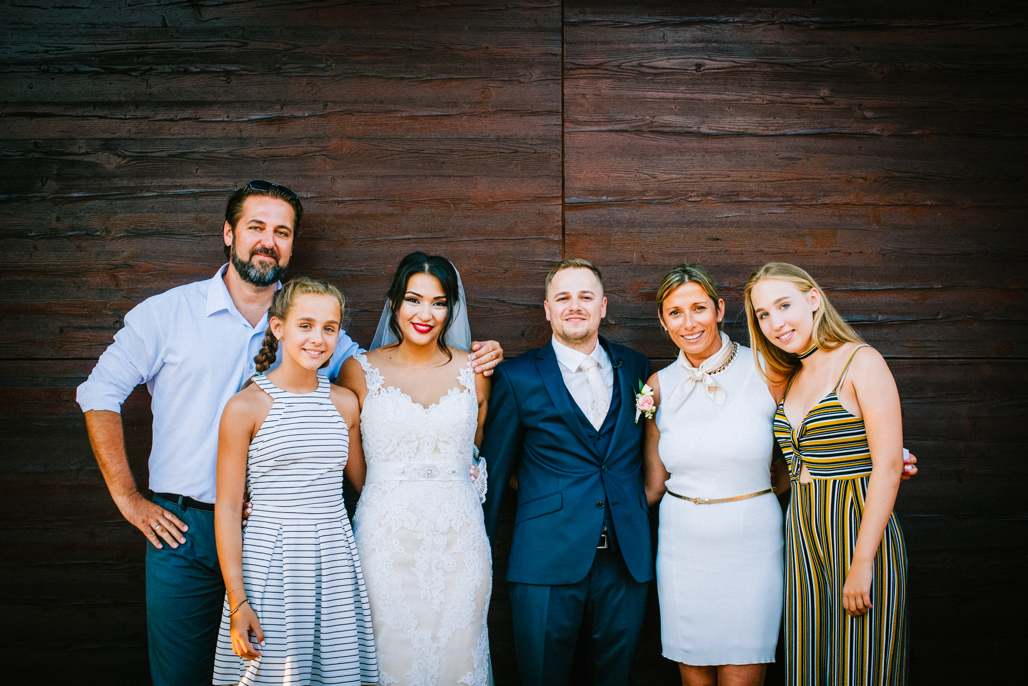 Bride and groom posing with extended family in elegant group portrait at wedding venue.