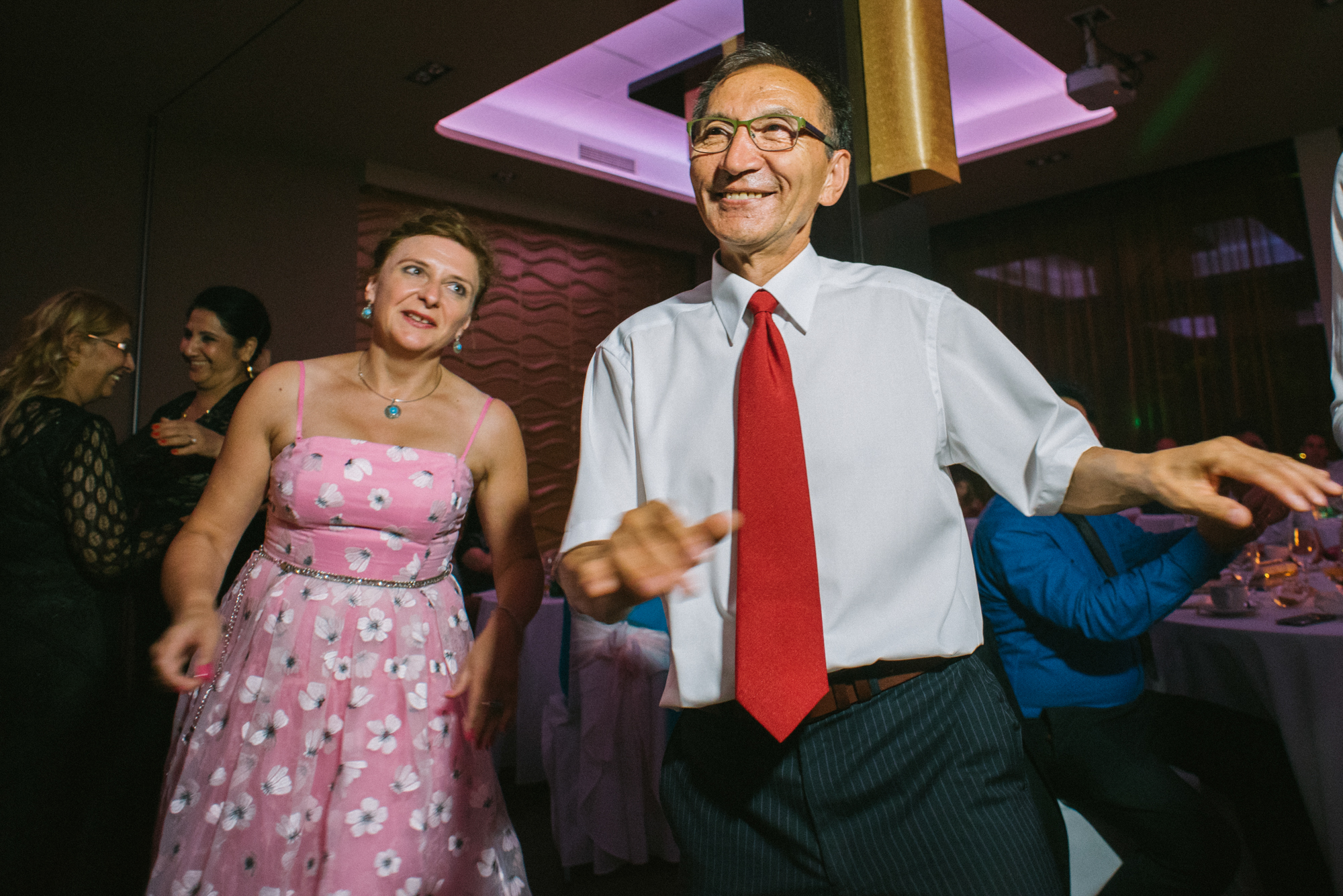 Wedding guests dancing together under colourful party lights during evening reception in Budapest.