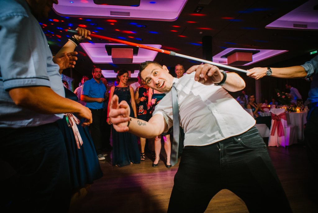 Guests playing limbo game on dance floor during fun wedding reception in Budapest venue.