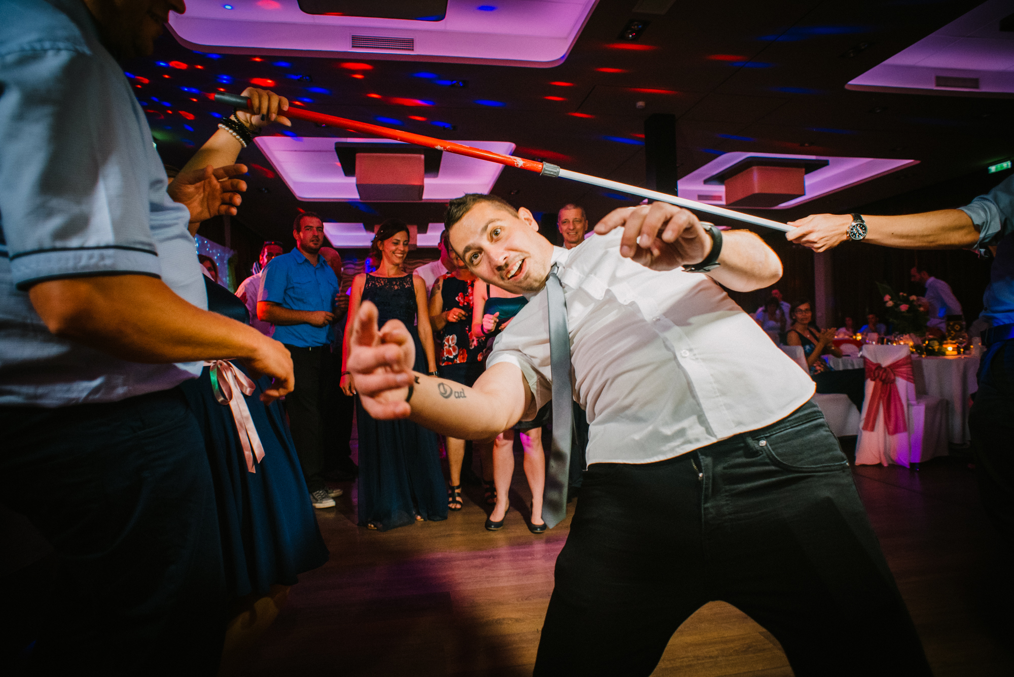 Guests playing limbo game on dance floor during fun wedding reception in Budapest venue.