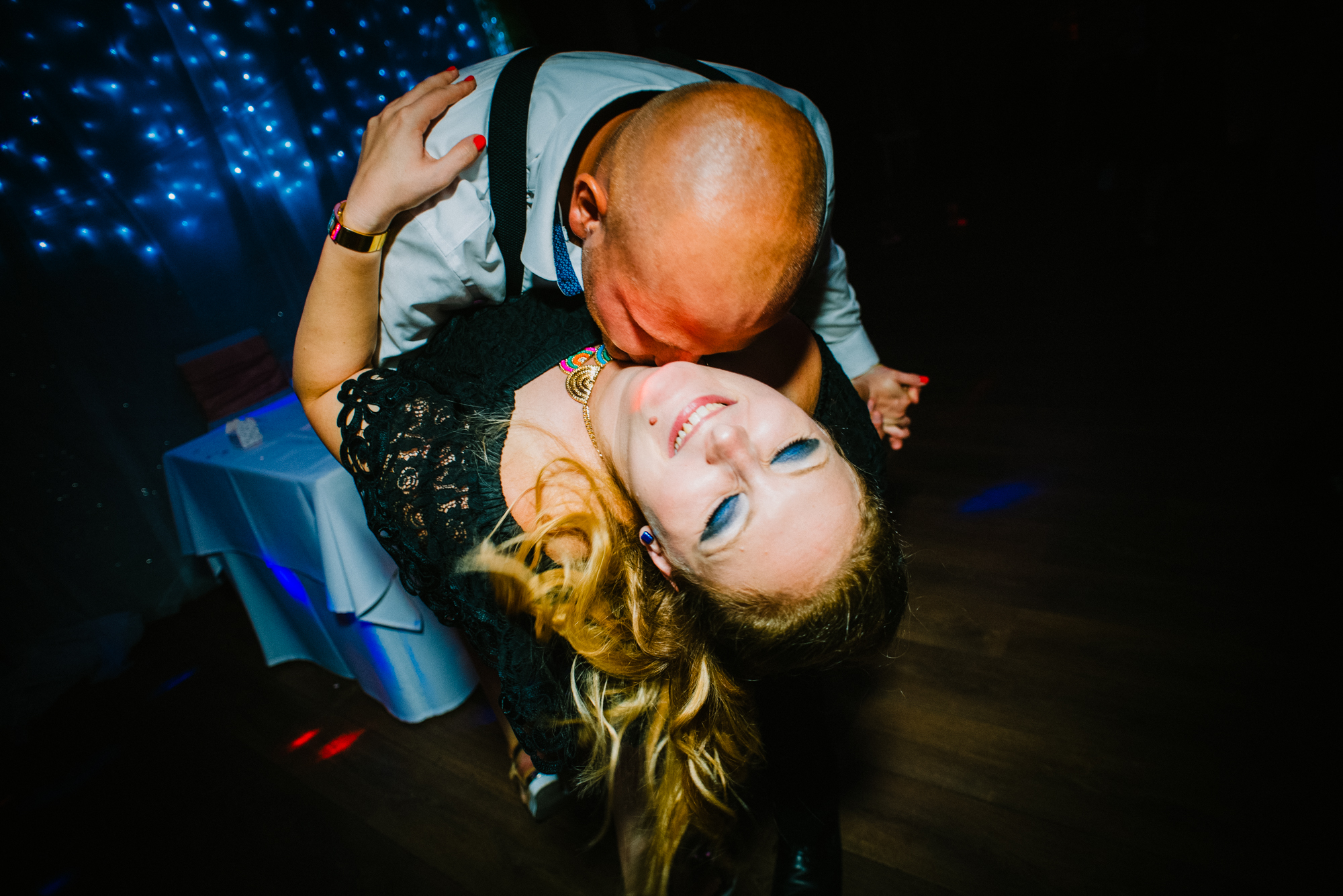 Wedding guest bending backwards during energetic dance floor moment.