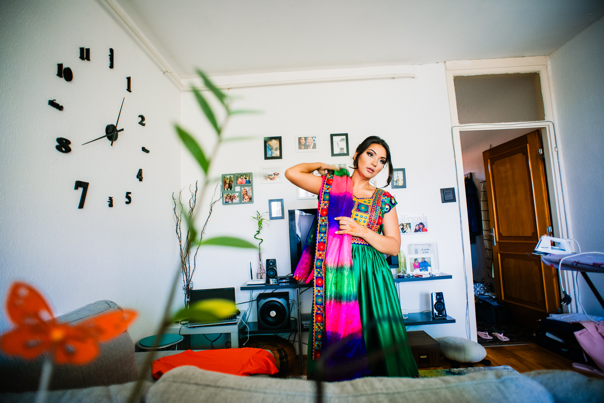 Bride adjusting colourful scarf in living room, relaxed candid pre-wedding moment.
