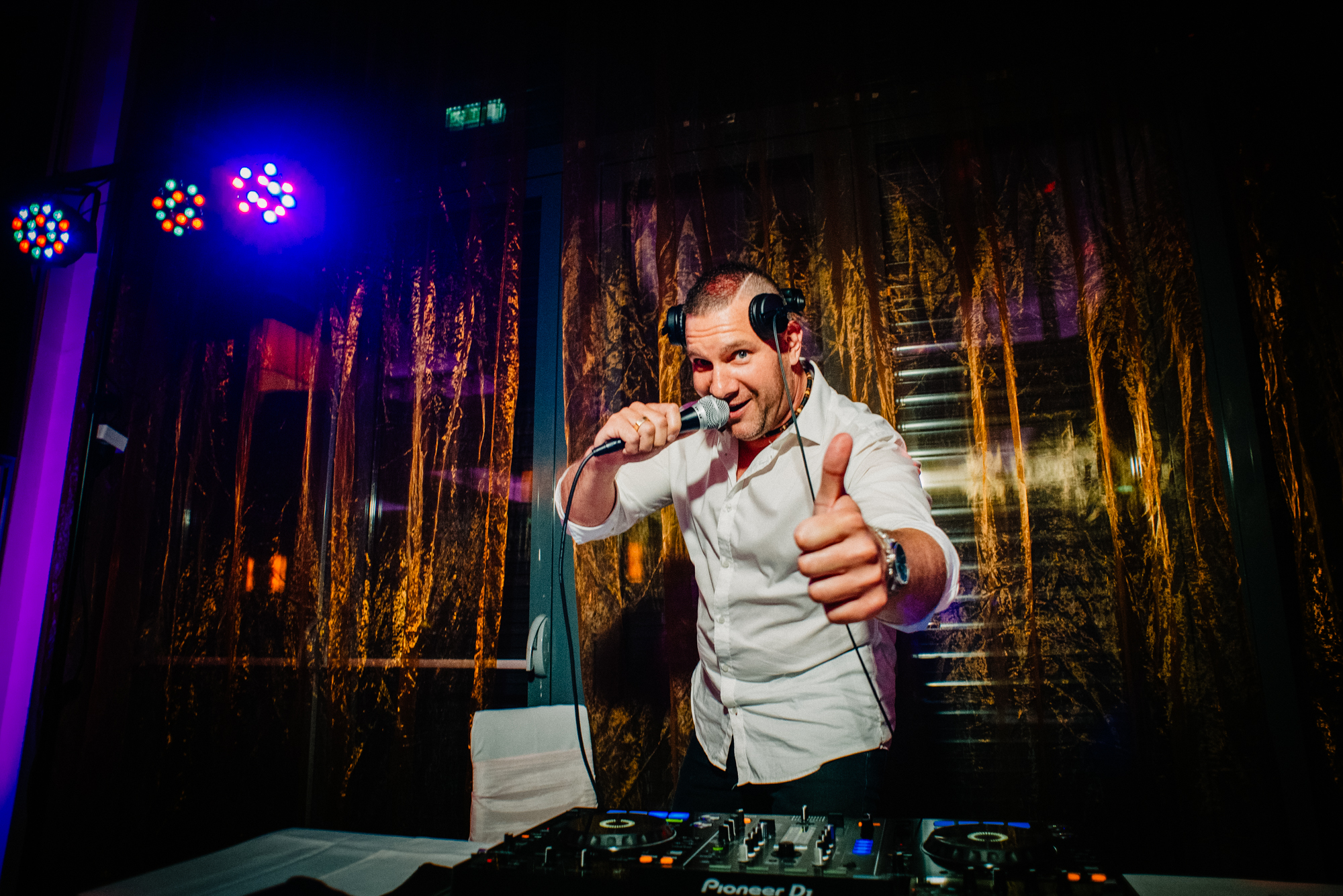 DJ performing and entertaining guests during wedding reception with music and lighting setup.