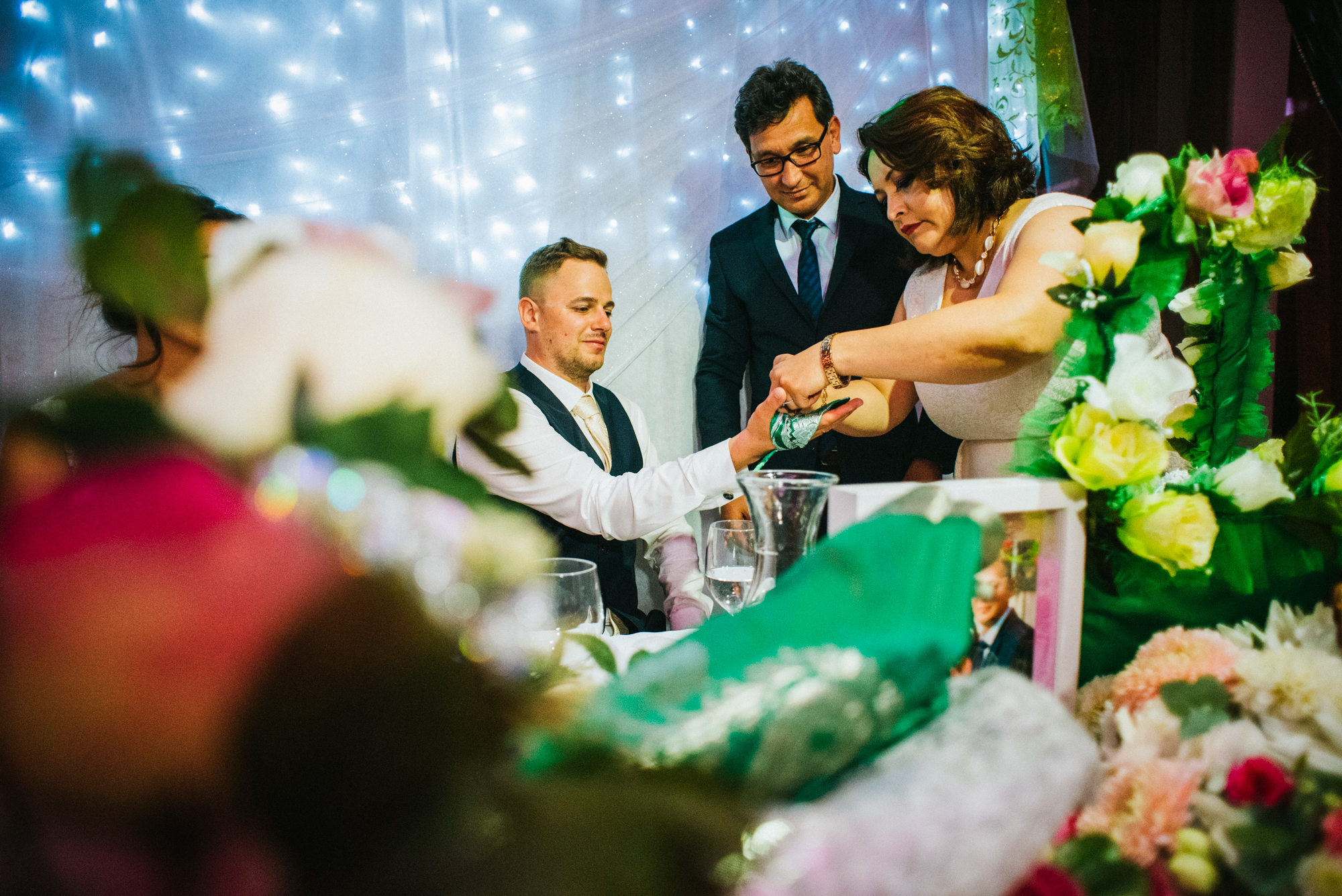 Wedding tradition moment with guests placing henna into groom’s hand during Budapest celebration.