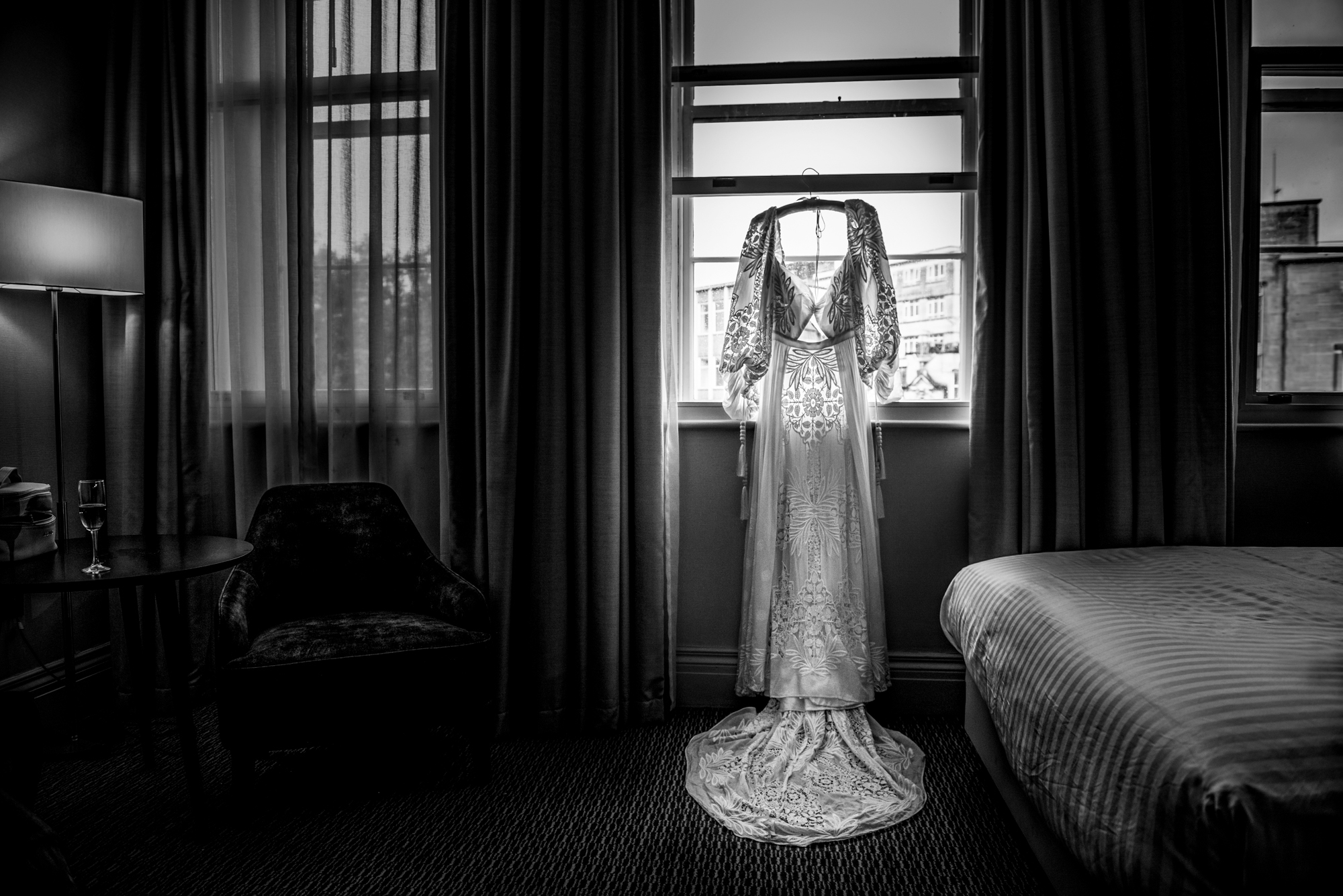Lace wedding dress hanging in window light at Bristol Marriott Royal Hotel.