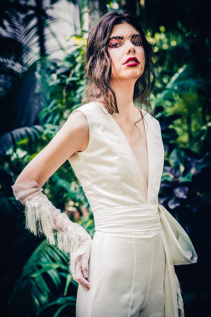 Close-up bridal portrait with bold makeup and birdcage veil in editorial shoot.