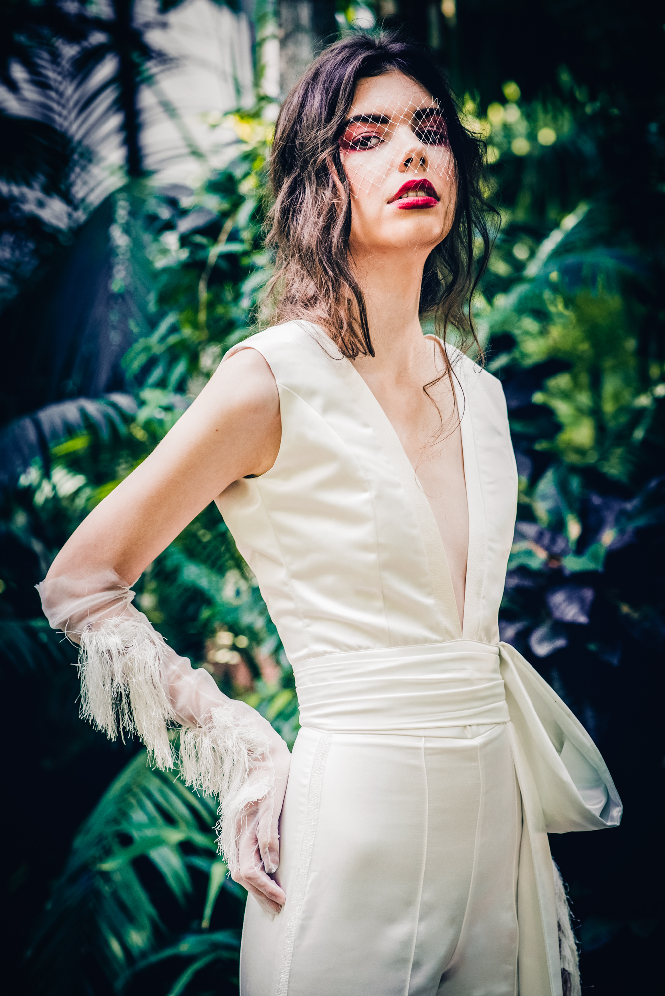 Close-up bridal portrait with bold makeup and birdcage veil in editorial shoot.