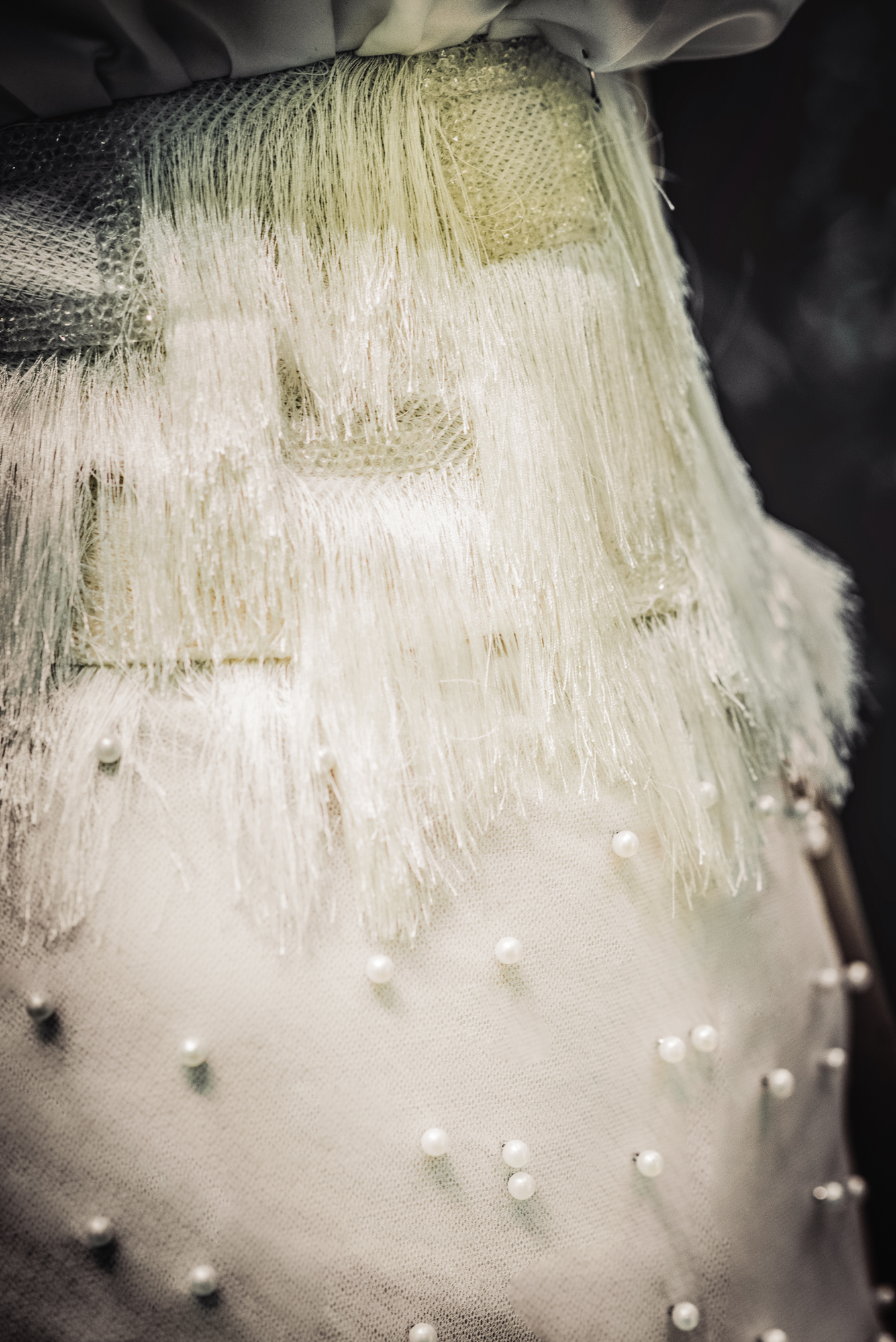 Detailed shot of bridal outfit with fringe layers and pearl embellishments.
