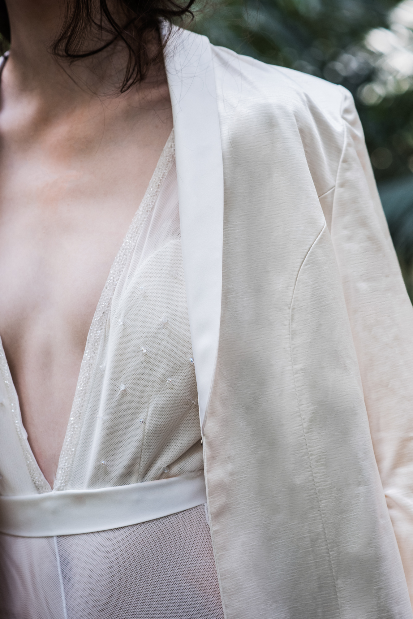 Close-up of bridal outfit neckline with sheer fabric and delicate embellishments.