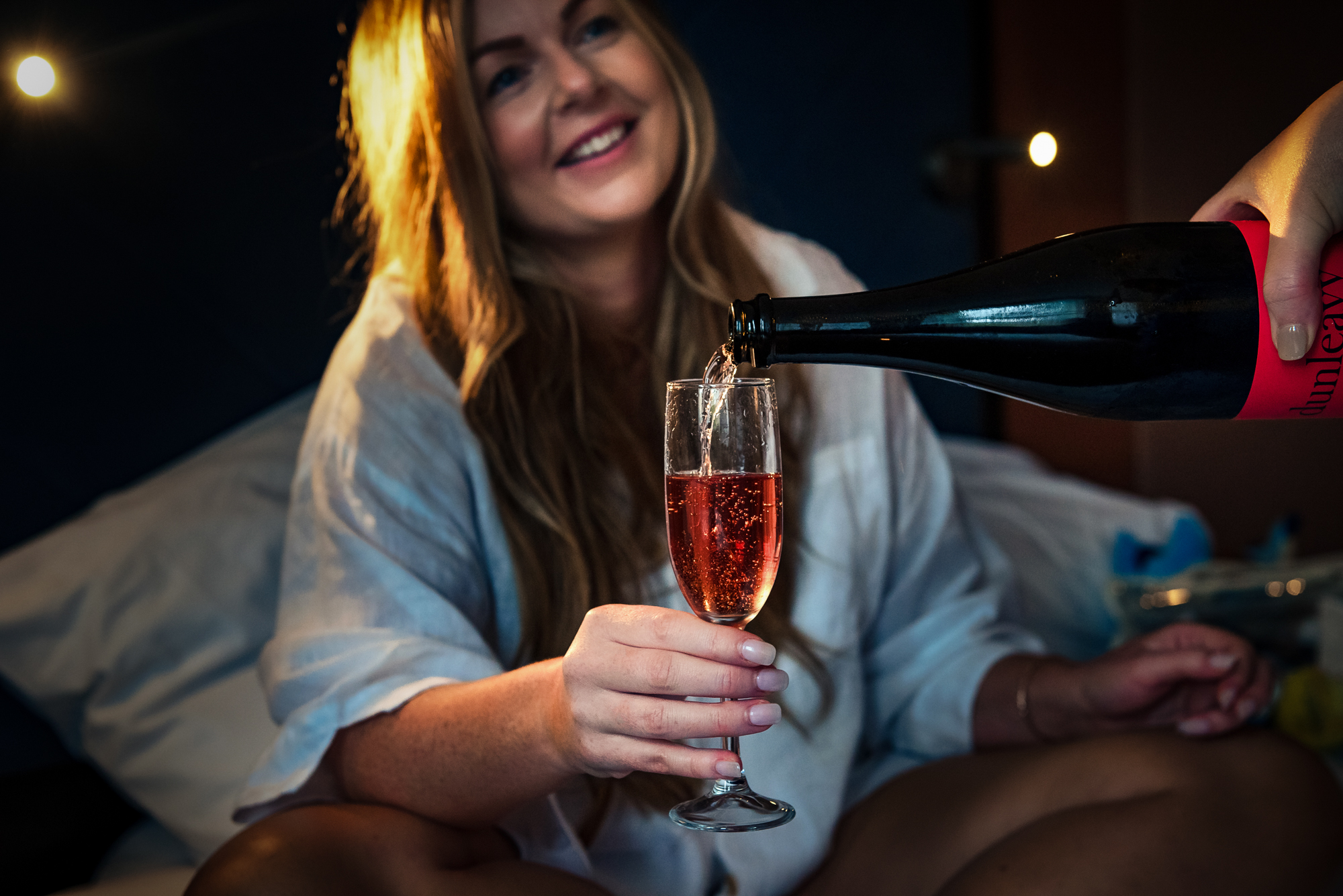 Woman pouring rosé champagne in hotel room during relaxed wedding morning at Bristol Marriott Royal Hotel in Bristol.