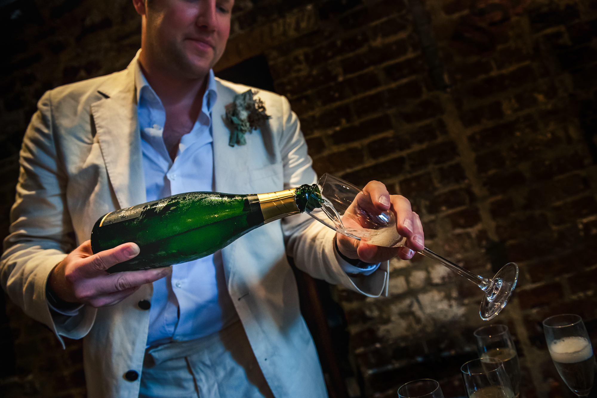 Guest pouring champagne into a glass during relaxed wedding reception.