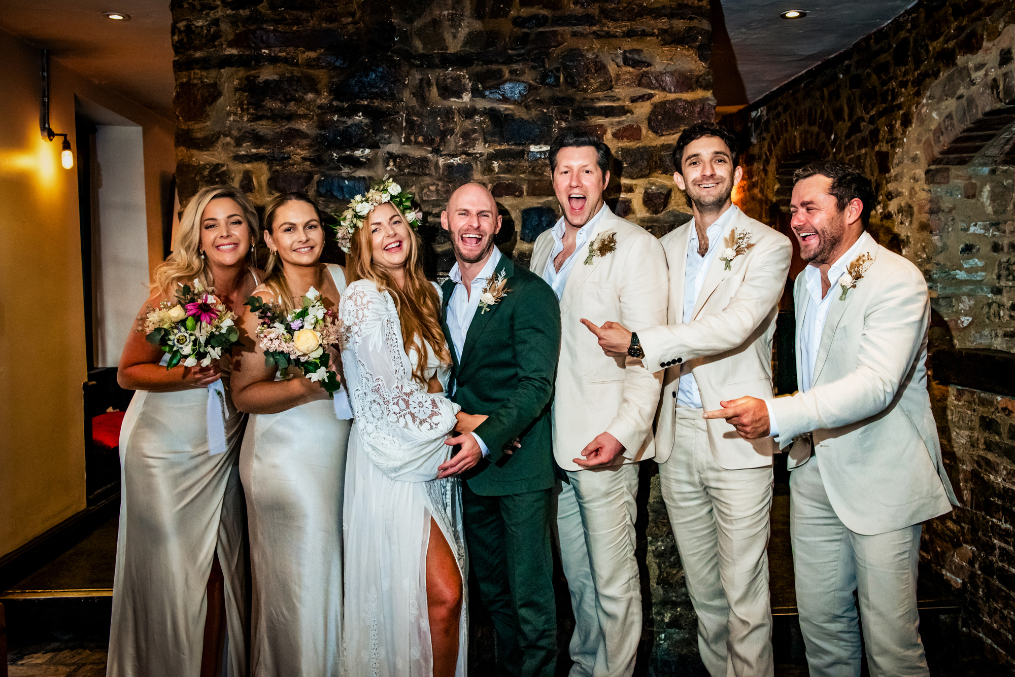 Wedding group portrait with bride and groom surrounded by joyful friends.