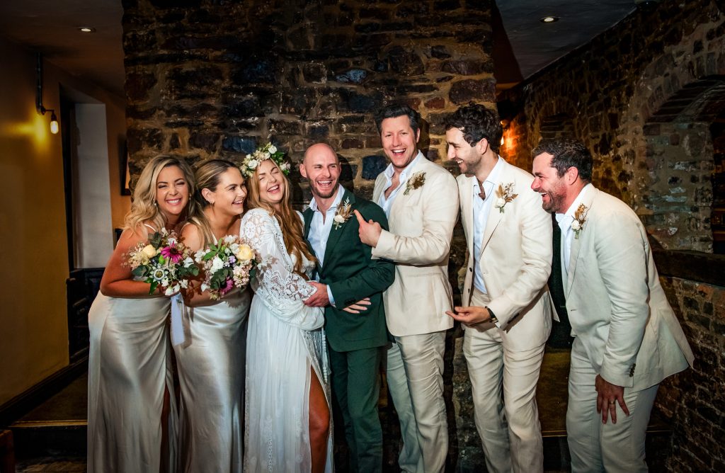 Wedding group portrait with bride and groom surrounded by their friends at the Christmas Steps Pub.