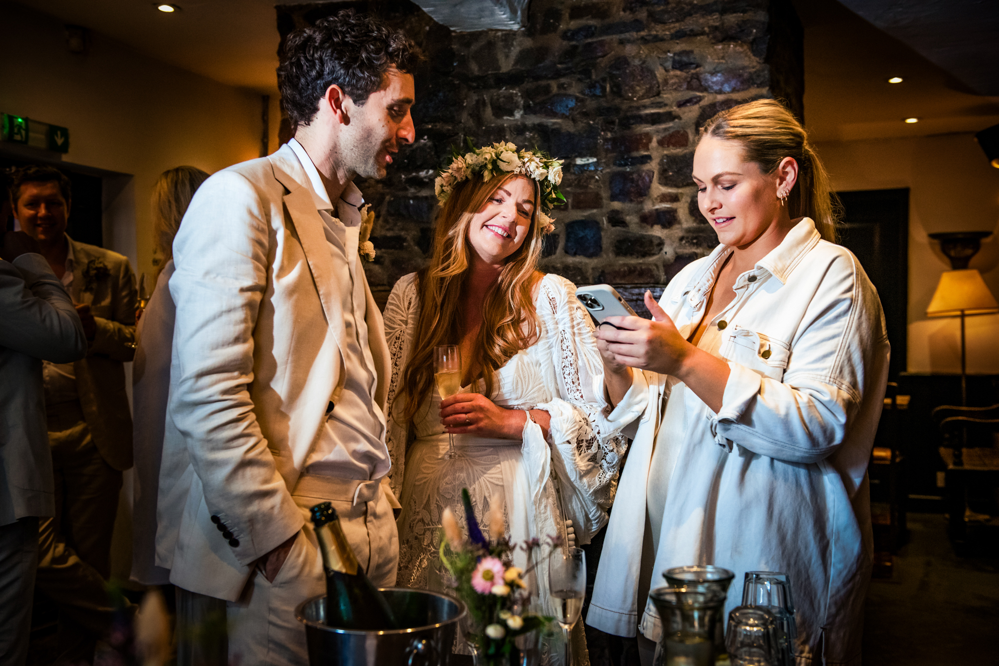 Bride and guests checking phone together during relaxed reception moment.