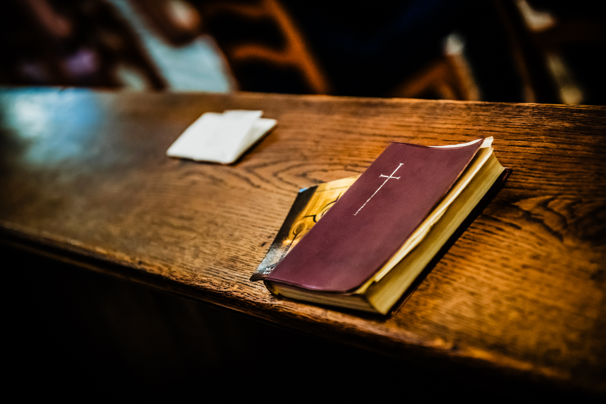 Prayer book resting on a wooden church bench during the christening service.