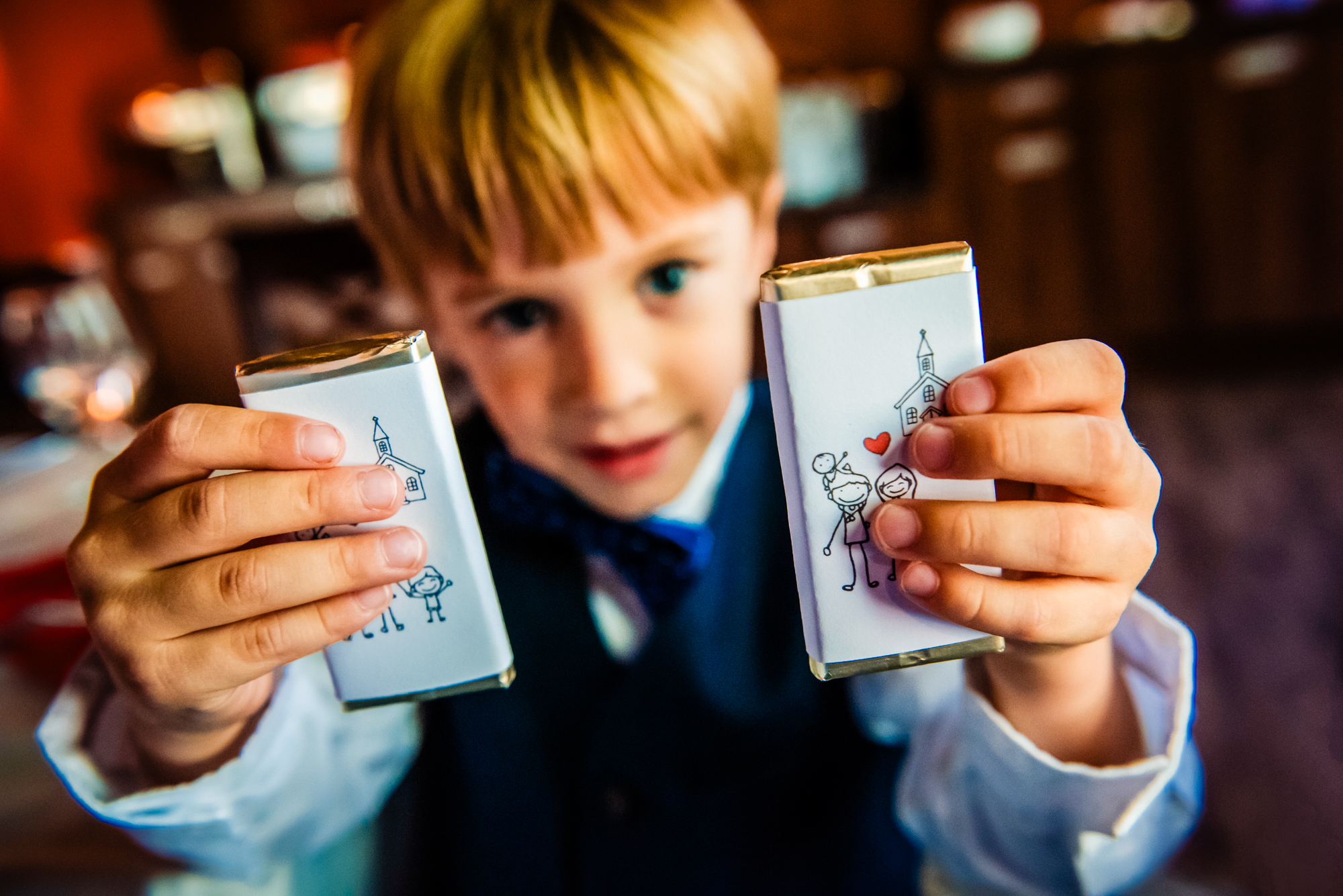 Little boy showing personalised chocolate favours at family christening reception.
